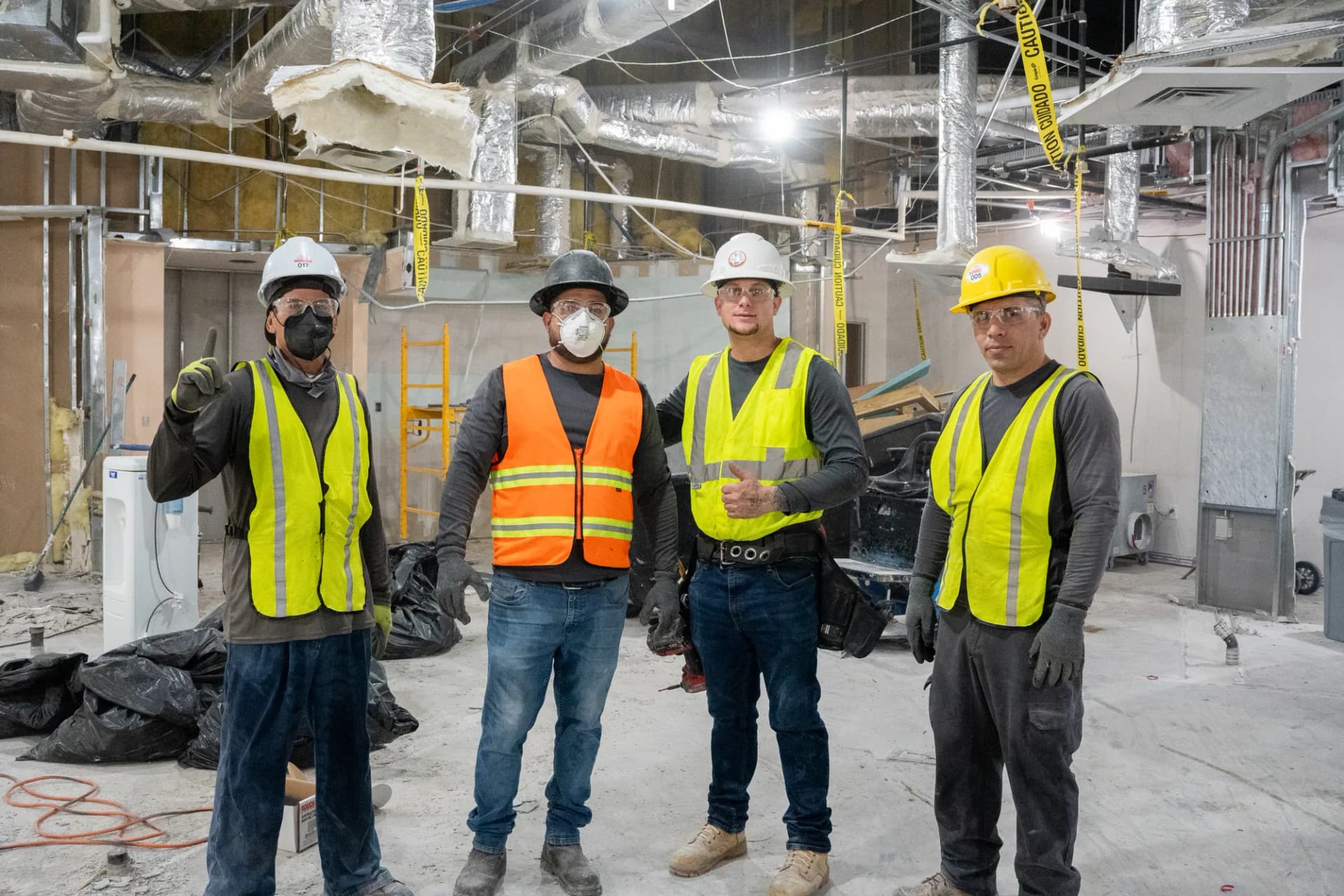 Four JZ field crew members wearing protective equipment inside an interior work area
